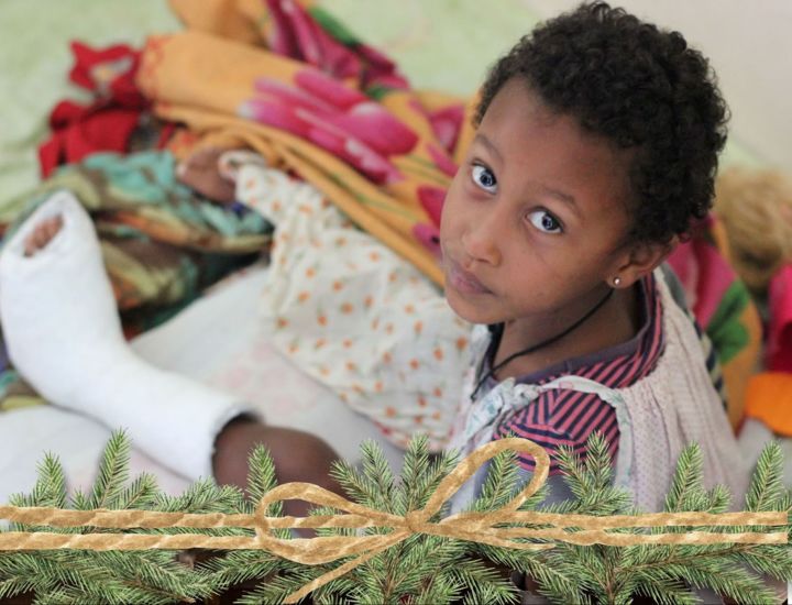 Girl sitting on bed with broken leg in cast