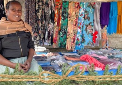 Ethiopian woman sitting at her clothing business stall on street